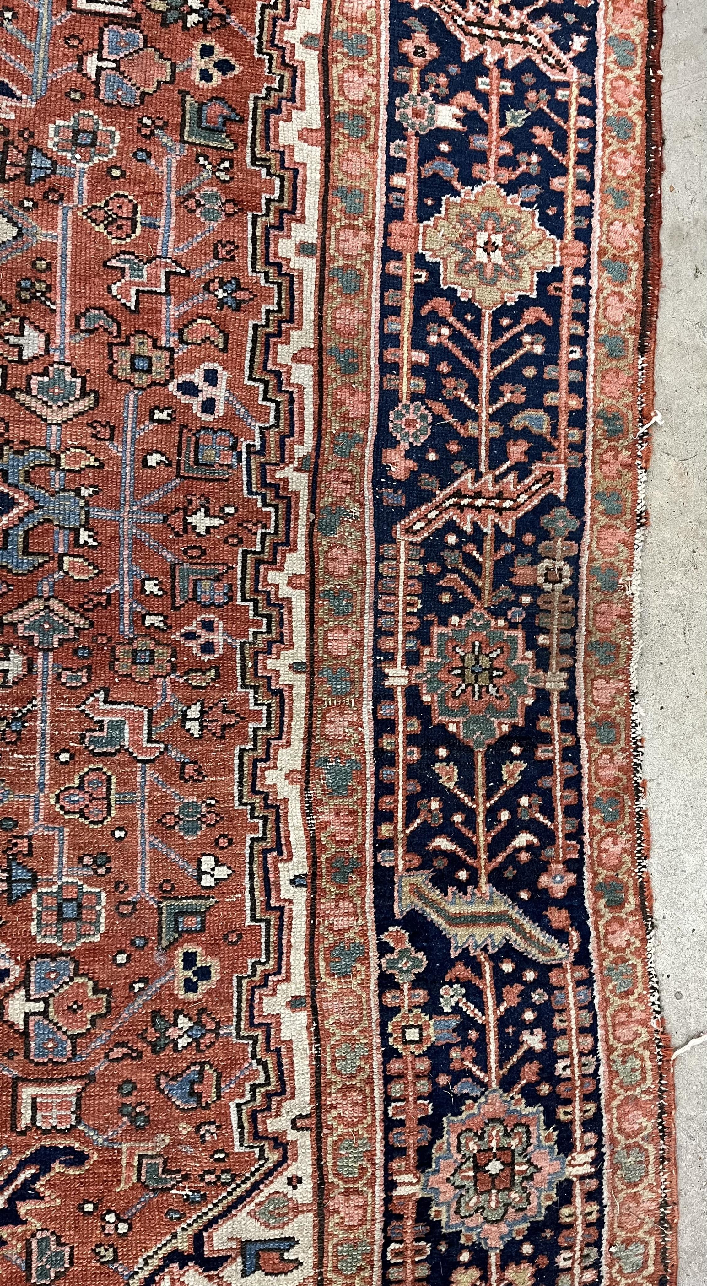 An antique Heriz brick red ground carpet, 350 x 274cm. Condition - fair